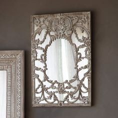 two mirrors are hanging on the wall next to each other, one is silver and the other is white