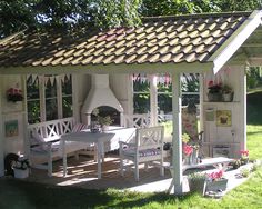 a small white shed with a table and chairs