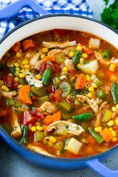 a blue pot filled with chicken vegetable soup on top of a white and blue towel