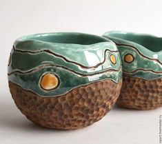 two ceramic bowls sitting side by side on a white surface with brown and green designs