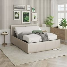 a white bed sitting on top of a wooden floor next to a wall mounted plant