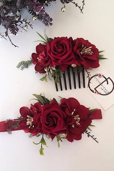 two combs with red flowers on them sitting next to some purple and white flowers