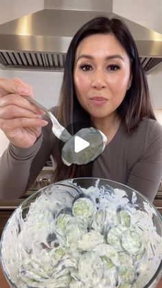 a woman holding a spoon over a bowl of food