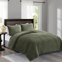 a bed with green bedspread and pillows in a room