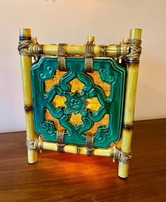 a green and yellow decorative object sitting on top of a wooden table next to a wall