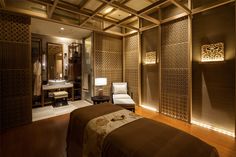 a spa room with a bed, chair and mirror