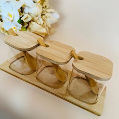 three wooden glasses sitting on top of a table next to a vase with flowers in it