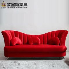 a red couch sitting on top of a white floor next to a wall with chinese writing