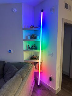 a living room with a couch and colorful lights on the wall in it's corner