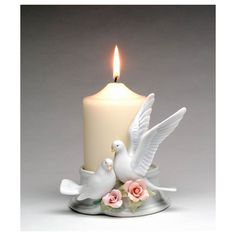 two white doves on a plate with a lit candle in the background and pink roses around it