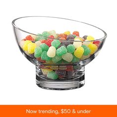 a glass bowl filled with gummy bears sitting on top of a black countertop