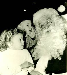 an old black and white photo of two children looking at santa claus's face