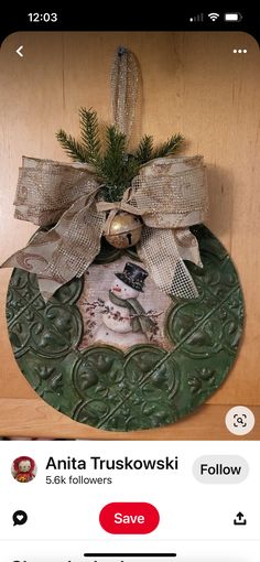 a christmas ornament hanging on a wooden wall with a bow and snowman