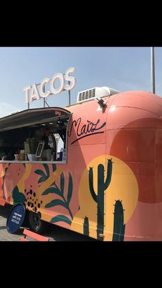 a taco truck parked in front of a building with cactus painted on the side