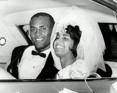 a bride and groom are sitting in the back of a car smiling at the camera