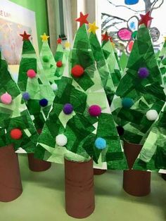 paper plate christmas trees with pom - poms on them in front of a bulletin board