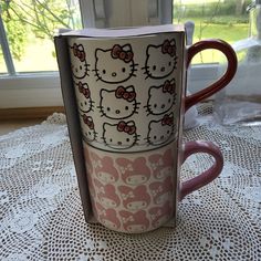 a hello kitty coffee cup sitting on top of a table next to an open window