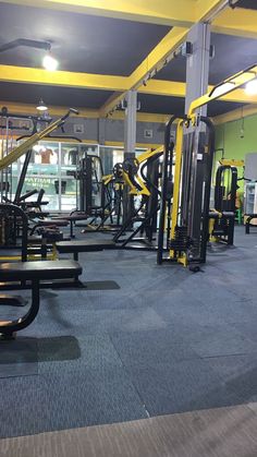 a gym with rows of exercise equipment in it's center floor and yellow accents