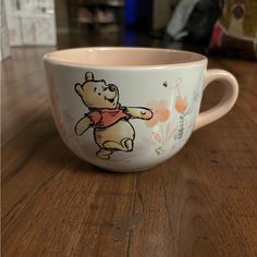 a winnie the pooh coffee cup sitting on top of a wooden table