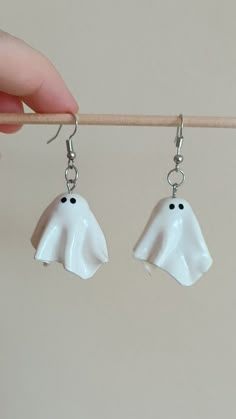 a pair of white ghost earrings hanging from a hook