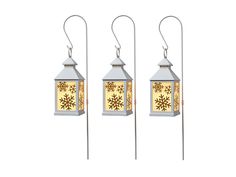 three white lanterns with snowflakes on them are hanging from metal poles, one is yellow and the other is silver