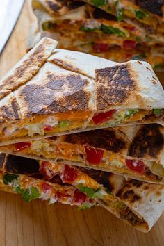 a stack of quesadillas sitting on top of a wooden table next to a knife