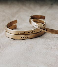 three brass bracelets with words on them