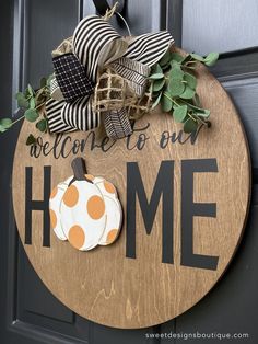 a welcome home sign on the front door with pumpkins and greenery around it