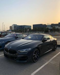 three bmw cars parked in a parking lot with buildings in the backgrouds