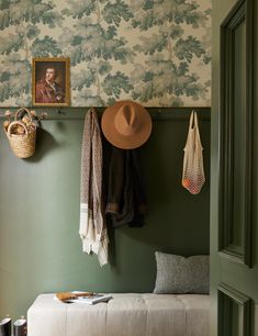 a bench with a hat on it next to a wall mounted coat rack and purse