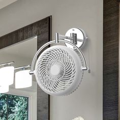 a white fan mounted to the side of a wall next to a mirror and sink