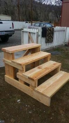 three wooden steps in front of a white fence