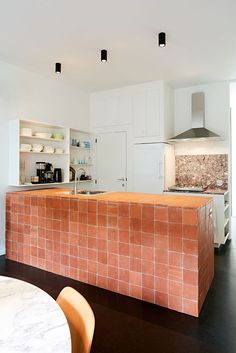 a kitchen with an island made out of red bricks and white cupboards on the wall