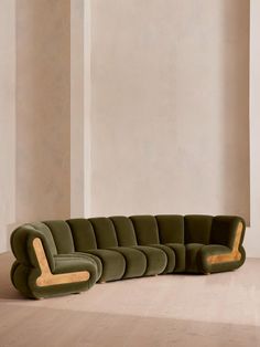 a green couch sitting on top of a hard wood floor next to a white wall