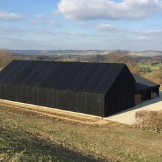 a large black barn sitting on top of a lush green field