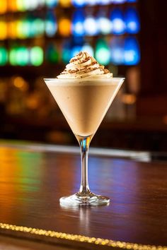 a small glass filled with ice cream on top of a wooden table next to a bar