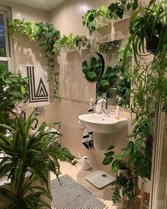 a bathroom filled with lots of greenery next to a sink