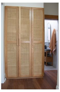 an open bamboo closet door in a room with wood flooring and white walls on the wall