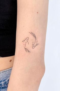 a woman's arm with a tattoo of two koi fish on the side