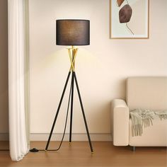 a living room with a white couch and a black lamp on top of a wooden floor