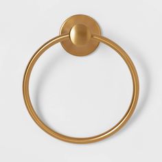 a gold towel ring on a white surface with a circular handle and an oval ball