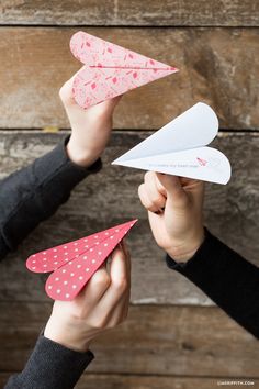 two people holding paper airplanes in their hands