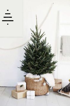 a small christmas tree in a wicker basket next to other presents on the floor