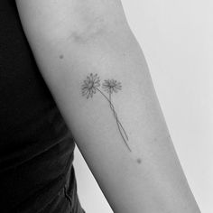 a black and white photo of a woman's arm with a flower tattoo on it