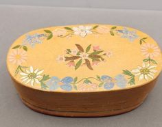 a small wooden box with flowers painted on the lid and sides, sitting on a table