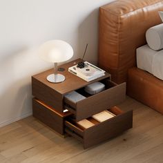 a small table with drawers in front of a bed next to a brown leather couch