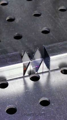 a metal object with holes in the middle and two triangles on it's side