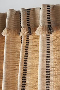 the curtains are lined up with black and white striped fabric on them, along with tassels