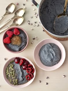 three bowls filled with different types of food on top of a wooden table next to spoons