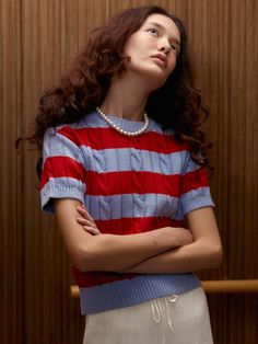 a woman standing in front of a wooden wall with her arms crossed and looking up